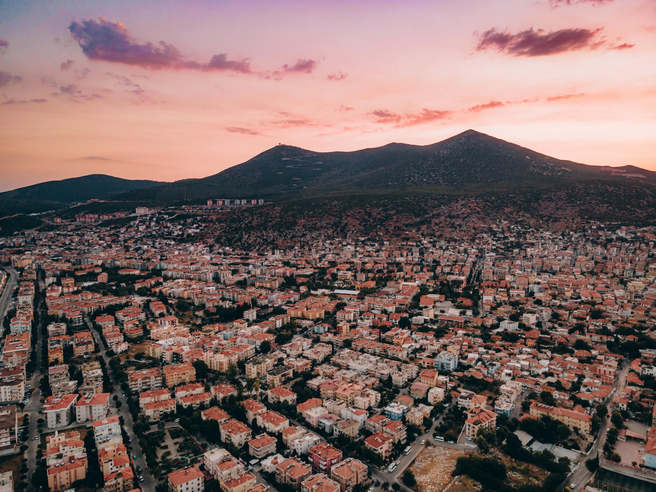 A stunning aerial view of Milas, Turkey, showcasing a vibrant residential area against a beautiful sunset sky.